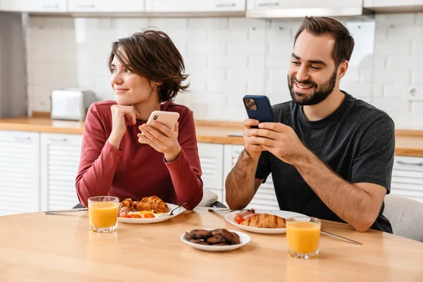 집에서 식사를 하면서 핸드폰을 사용하는 부부들 — 스톡 사진