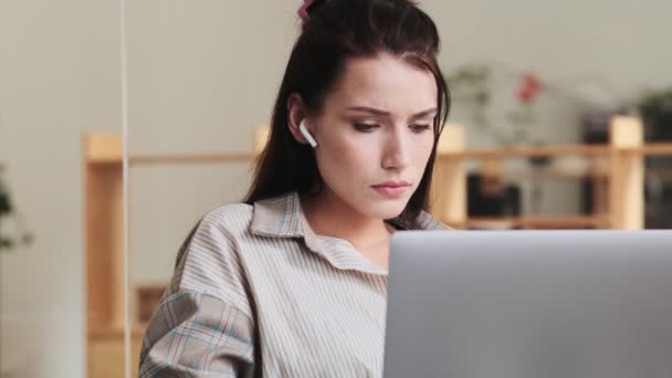 Kulaklık Takan Düşünceli Bir Kadını Ofiste Laptopuyla Oturuyor — Stok video