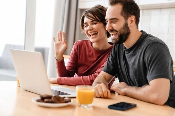 Emocionado Joven Pareja Haciendo Gestos Utilizando Ordenador Portátil Mientras Sienta —  Fotos de Stock