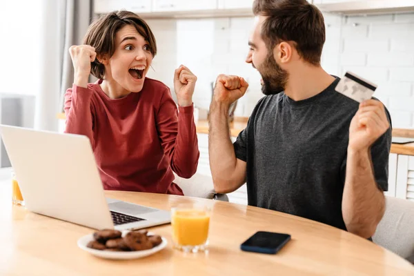 Encantada Pareja Joven Que Utiliza Ordenador Portátil Tarjeta Crédito Mientras —  Fotos de Stock