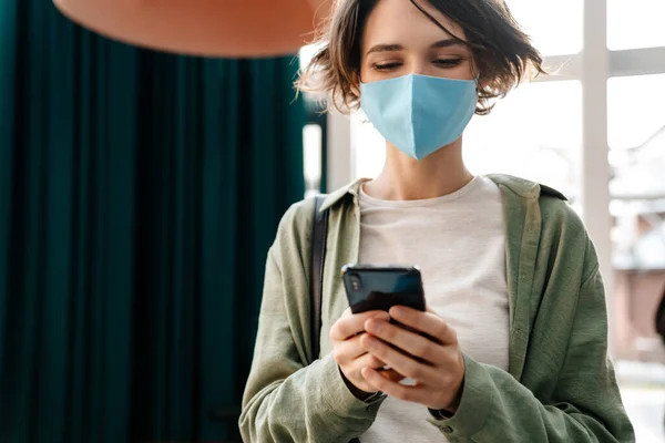 Menina Feliz Máscara Protetora Usando Celular Enquanto Está Dentro Casa — Fotografia de Stock