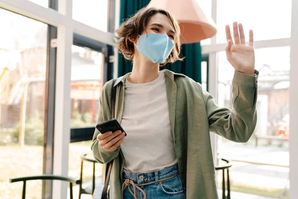 Menina Feliz Máscara Protetora Acenando Mão Usando Celular Enquanto Estava — Fotografia de Stock