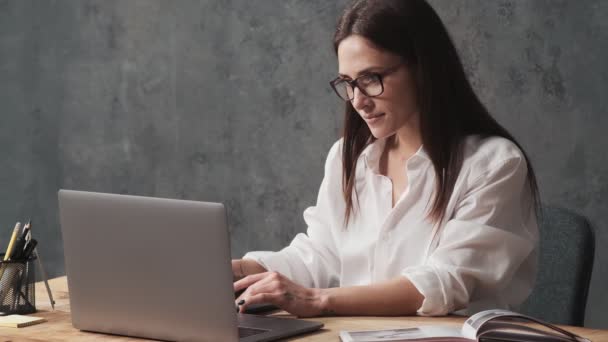 Een Geconcentreerde Zakenvrouw Met Een Bril Gebruikt Haar Laptop Terwijl — Stockvideo