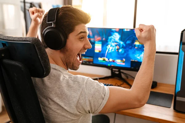 Ενθουσιασμένος Τύπος Ακουστικά Κάνει Χειρονομία Νικητής Παίζοντας Βιντεοπαιχνίδι Στον Υπολογιστή — Φωτογραφία Αρχείου