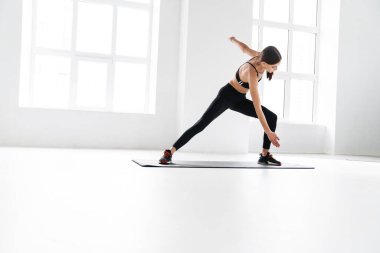 Sporcu genç bayan paspasın üzerinde çalışırken egzersiz yapıyor.