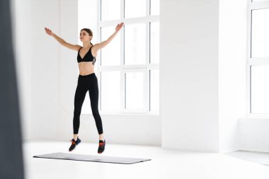 Kapalı alanda spor yaparken atlayan genç ve keyifli bir sporcu.