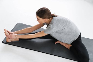 Sporcu genç bayan paspasın üzerinde çalışırken egzersiz yapıyor.