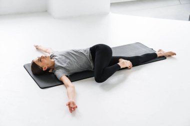 Atletik odaklı sporcu kadın içeride yoga yaparken egzersiz yapıyor.