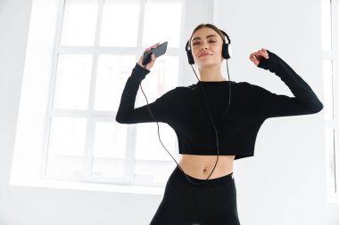 Kulaklık ve akıllı telefonla müzik dinlerken dans eden mutlu bir kadın.