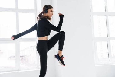 Kulaklıklı atletik genç bayan içeride çalışıyor.