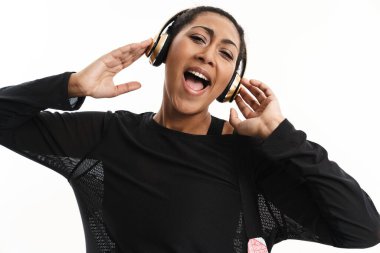 Beyaz arka planda izole edilmiş kulaklıklarla müzik dinleyen mutlu Afrikalı Amerikalı kadın.
