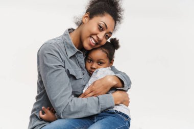 Afrikalı anne ve kız birlikte gülüyor ve sarılıyorlar. Beyaz duvarın üzerinde izole edilmiş.