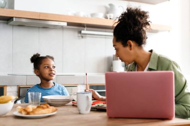 Zenci anne ve kızı evdeki mutfakta birlikte kahvaltı ediyorlar.