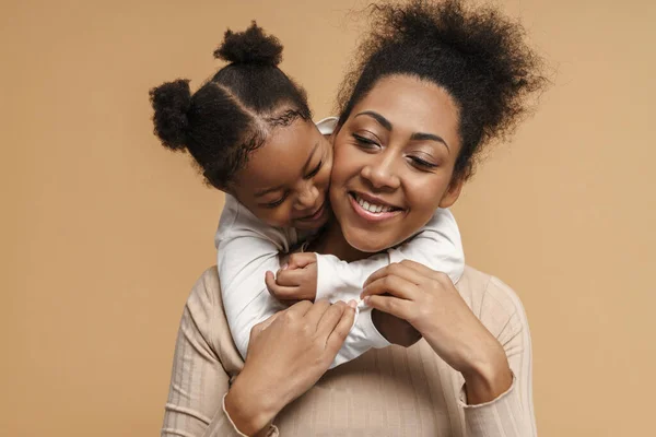 Happy black mother and daughter hugging while making fun together isolated over beige background