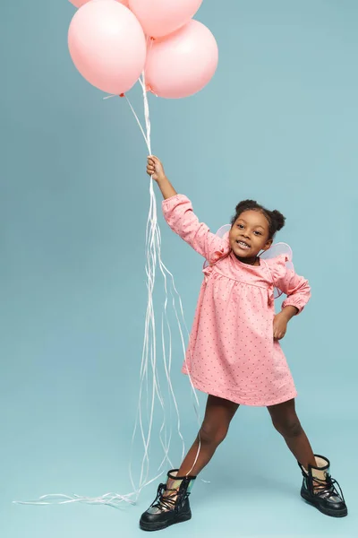 Ευτυχισμένο Μαύρο Κορίτσι Φτερά Παιχνιδιού Ποζάρουν Ροζ Μπαλόνια Απομονώνονται Μπλε — Φωτογραφία Αρχείου