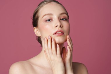 Pembe arka planda izole edilmiş güzel bir genç kadının portresi.