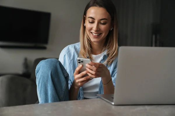 Happy Young Woman Using Mobile Phone While Sitting Home Laptop — Stock Photo, Image