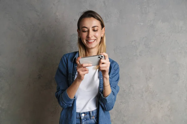 Χαμογελώντας Ελκυστική Νεαρή Γυναίκα Χρησιμοποιώντας Κινητό Τηλέφωνο Ενώ Στέκεται Απομονωμένη — Φωτογραφία Αρχείου