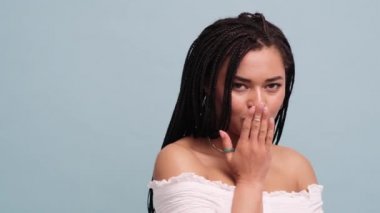 Mutlu bir Afrikalı Amerikalı kadın, stüdyodaki gri duvardan izole edilmiş bir öpücük gönderiyor.