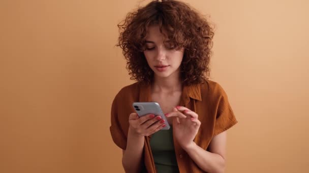 Una Mujer Complacida Con Pelo Rizado Está Utilizando Teléfono Inteligente — Vídeos de Stock