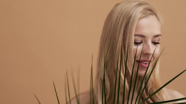 Красивая Блондинка Позирует Пальмовыми Листьями Стоящими Изолированно Над Бежевой Стеной — стоковое видео
