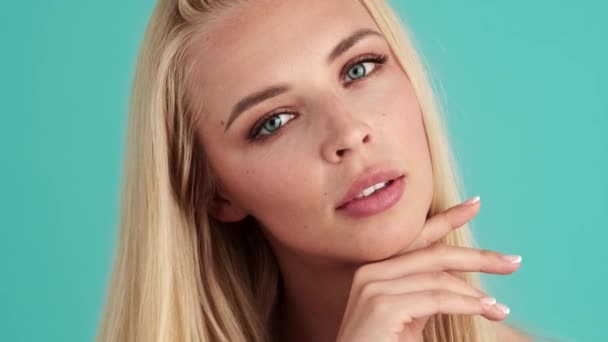 Piękna Młoda Blondynka Spogląda Kamerę Stojącą Niebieskiej Ścianie Studio — Wideo stockowe