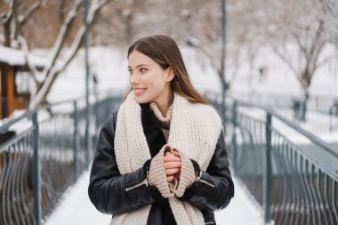 Kışlık ceketli güzel bir kadın köprüde dikilip havanın tadını çıkarıyor.