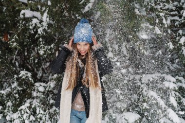 Kışlık ceketli mutlu ve çekici bir kadın açık havada eğleniyor.