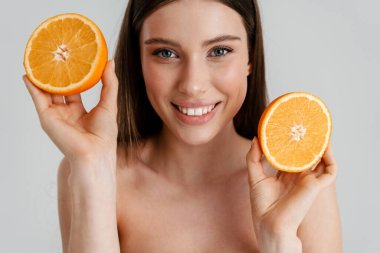 Beyaz arka planda turuncuyla poz verirken gülümseyen mutlu üstsüz kız.