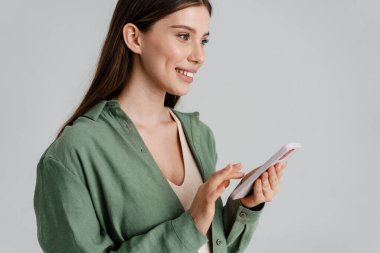 Beyaz arka planda izole edilmiş, gülümseyen ve cep telefonu kullanan mutlu beyaz kız.