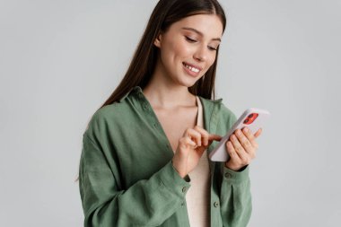 Beyaz arka planda izole edilmiş, gülümseyen ve cep telefonu kullanan mutlu beyaz kız.