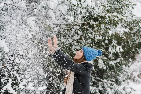 在冬天的森林里散步的时候 戴着针织帽子和雪开玩笑的美丽的快乐姑娘 — 图库照片