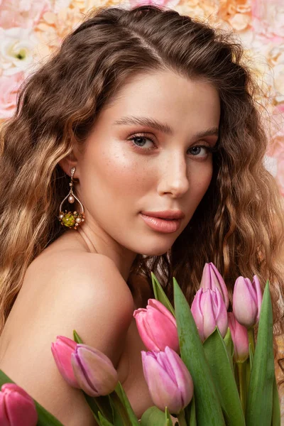 半裸的年轻女子 头戴耳环 头戴郁金香形耳环 背景为花朵 — 图库照片