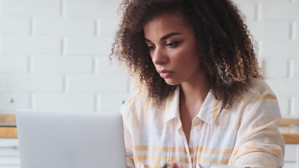 集中アフリカ系アメリカ人の女性が自宅で仕事をしながらノートパソコンを使っています — ストック動画