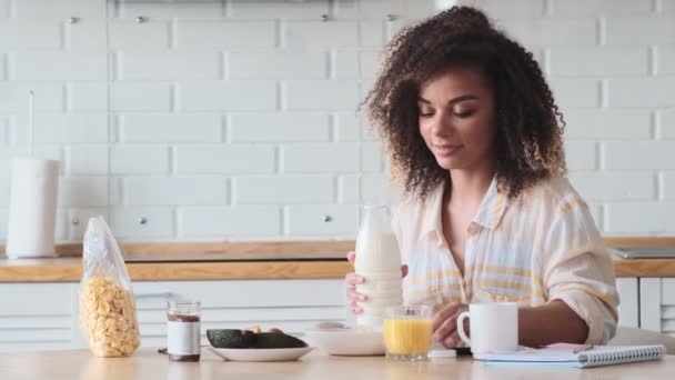 Een Gelukkige Afro Amerikaanse Vrouw Ontbijt Terwijl Melk Kom Giet — Stockvideo