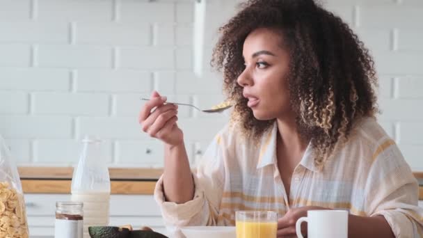 Una Mujer Afroamericana Complacida Está Comiendo Hojuelas Con Leche Sentada — Vídeo de stock