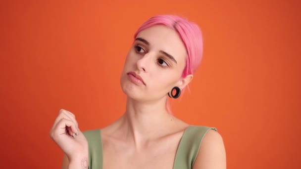 一位有着一头粉红头发的有思想的年轻女子正凝视着工作室里被隔离在橙色墙外的一边 — 图库视频影像