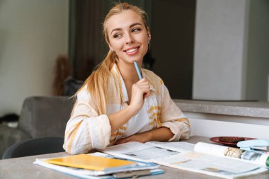 Gülümseyen çekici kız evde ders çalışıyor.