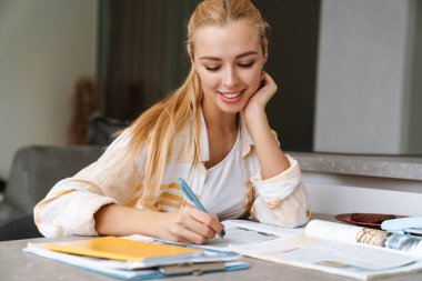 Gülümseyen çekici kız evde ders çalışıyor.