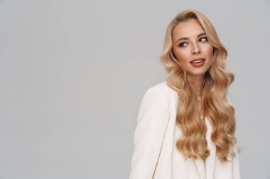 Gri arka planda yalnız başına poz veren güzel, şık bir kız.