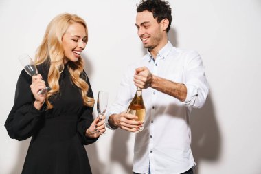 Beyaz arka planda izole edilmiş şampanya içerken gülümseyen mutlu romantik çift.