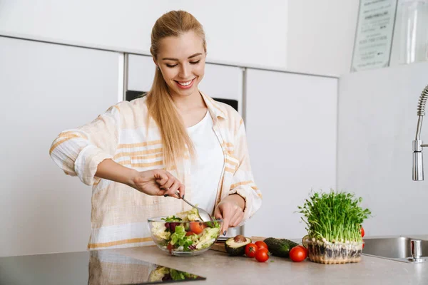 Mulher Loira Alegre Sorrindo Enquanto Prepara Salada Fresca Cozinha Doméstica — Fotografia de Stock