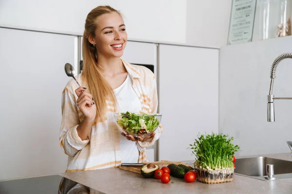 Mulher Loira Alegre Sorrindo Enquanto Prepara Salada Fresca Cozinha Doméstica — Fotografia de Stock