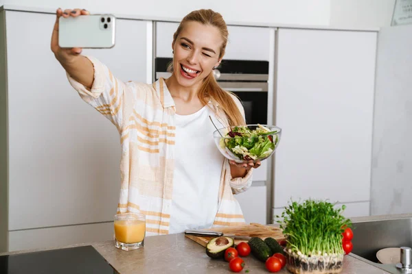 Mulher Loira Alegre Tomando Selfie Celular Com Salada Fresca Cozinha — Fotografia de Stock