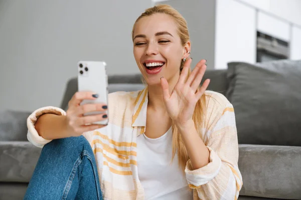 Glückliche Blonde Frau Winkt Mit Der Hand Während Sie Hause — Stockfoto