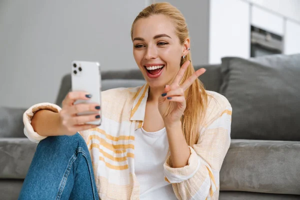 Mutlu Sarışın Kadın Evde Cep Telefonuyla Selfie Çekerken Barış Işareti — Stok fotoğraf