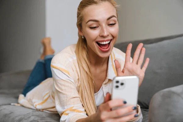 Щаслива Блондинка Махає Рукою Використовує Мобільний Телефон Дивані Вдома — стокове фото