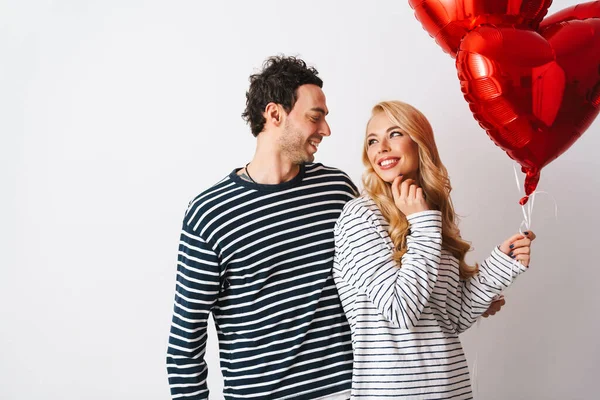 Ευτυχισμένο Ρομαντικό Ζευγάρι Χαμογελά Ενώ Ποζάρουν Μπαλόνια Καρδιά Απομονώνονται Λευκό — Φωτογραφία Αρχείου