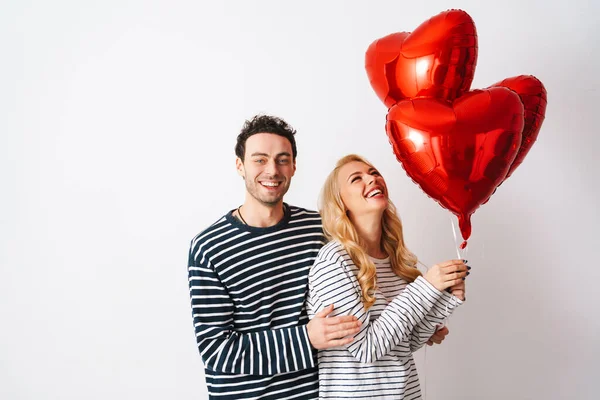 Ευτυχισμένο Ρομαντικό Ζευγάρι Γελώντας Ενώ Ποζάρουν Μπαλόνια Καρδιά Απομονώνονται Λευκό — Φωτογραφία Αρχείου