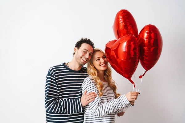 Ευτυχισμένο Ρομαντικό Ζευγάρι Χαμογελά Ενώ Ποζάρουν Μπαλόνια Καρδιά Απομονώνονται Λευκό — Φωτογραφία Αρχείου